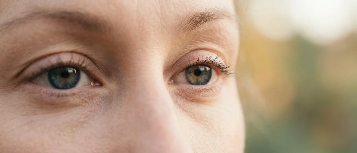 Close-up of calm softly unfocused eyes with a blurred warm background, representing open-eye meditation practice